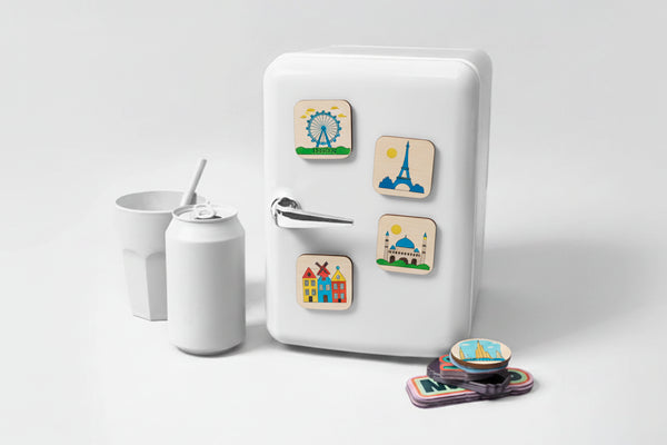 Small white refrigerator with colorful magnets on a light gray background